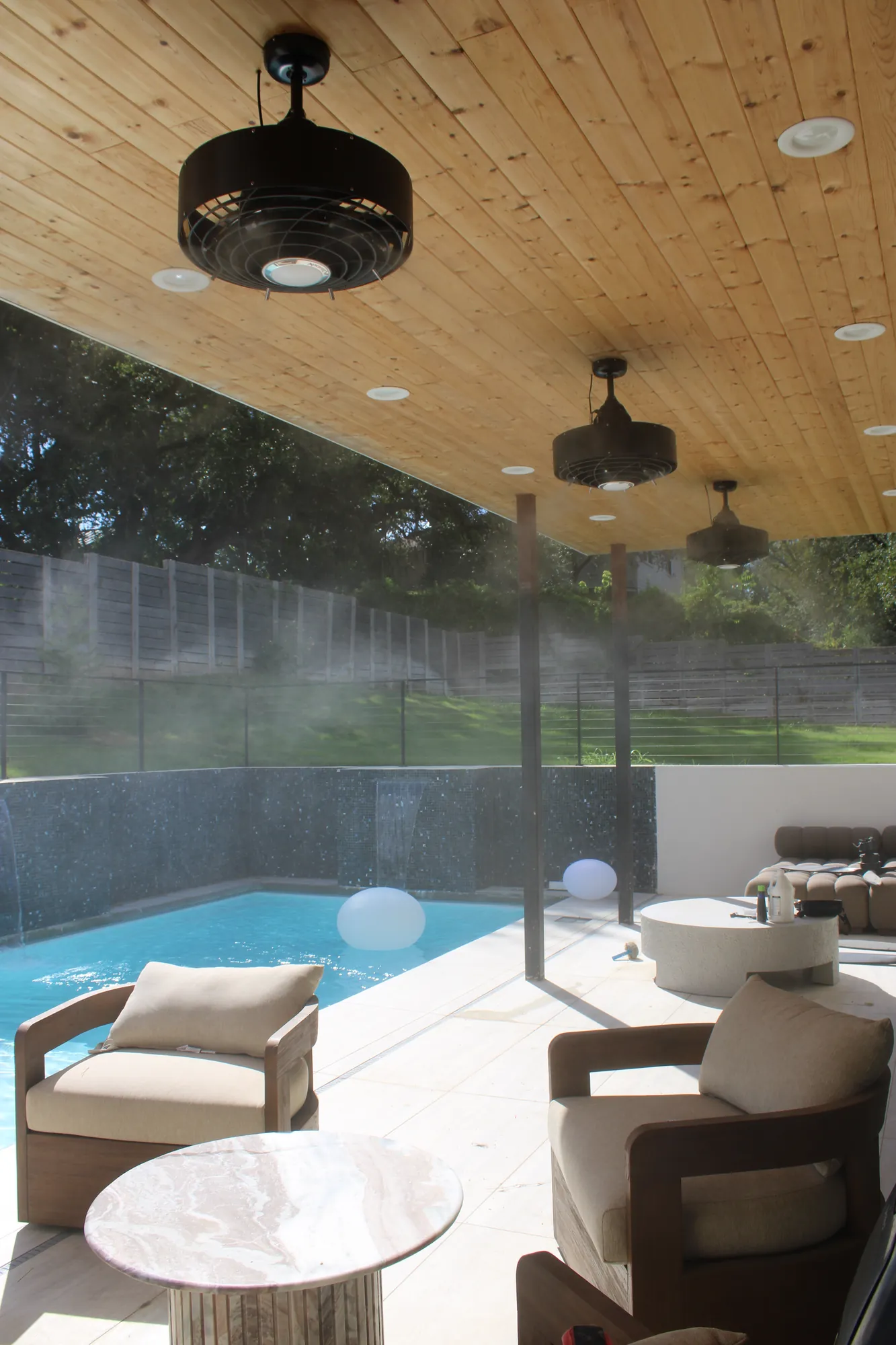 Misting fans on a pool patio with wood ceiling