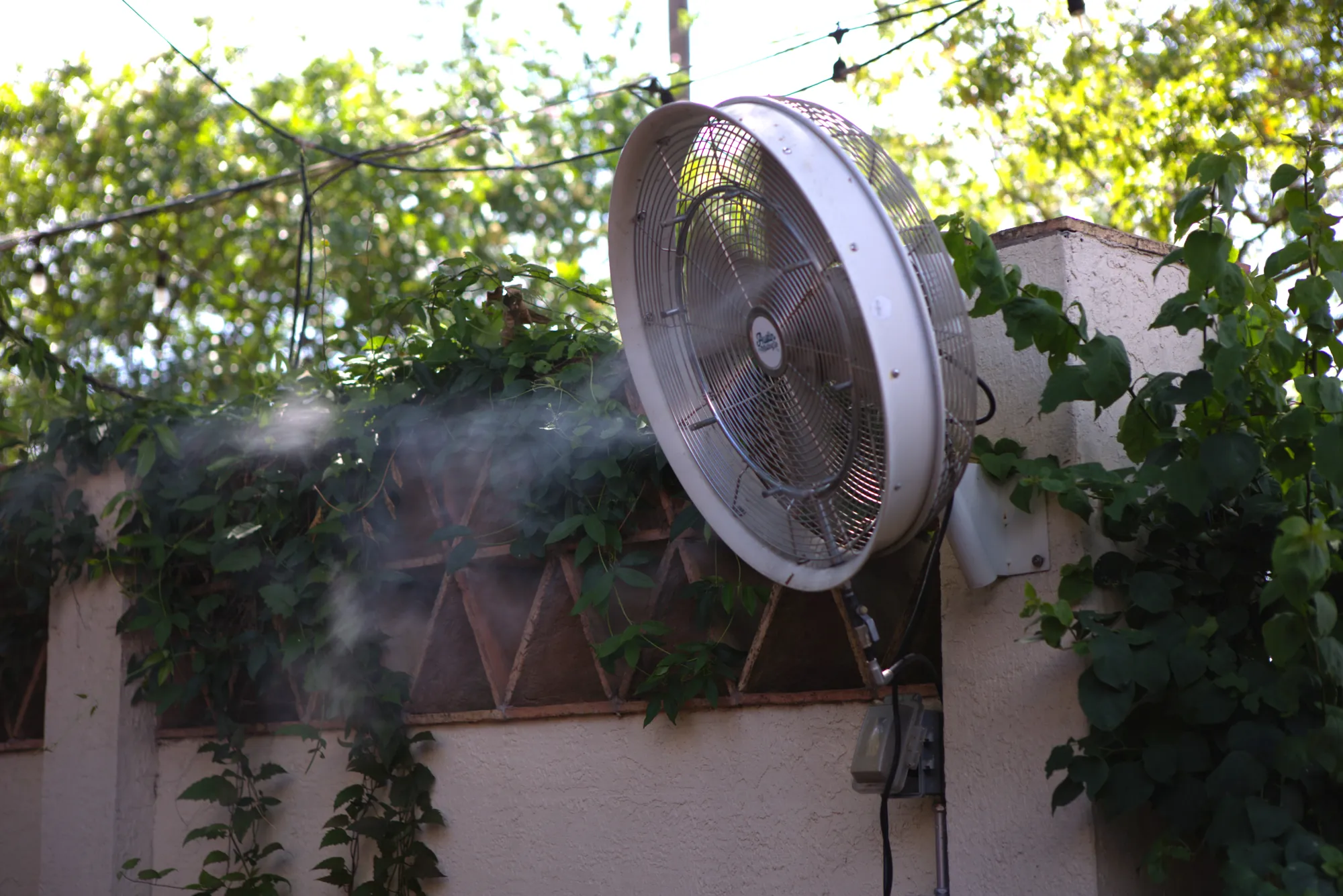 Wall-mounted misting fan on a courtyard patio